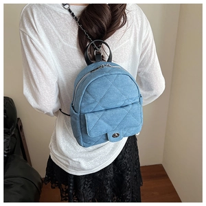 Detail of blue denim quilted mini backpack with silver twist lock and chain strap