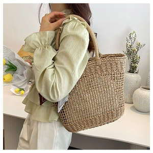 Detail of hand-woven hollow straw tote bag with round handles for summer beach vacations