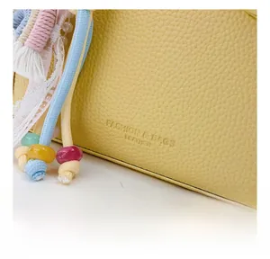Detailed macro view of yellow lychee grain leather bag with colorful beaded tassels
