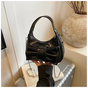 Détail du sac croissant noir avec grand nœud décoratif et bandoulière chaîne argent