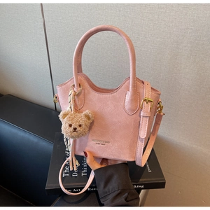 Dettaglio della borsa a secchiello in pelle plissettata rosa chiaro con ciondolo a orso