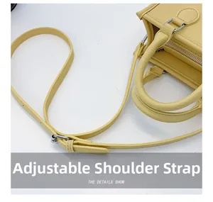 Detail view of yellow lychee leather handbag with adjustable shoulder strap and top handle