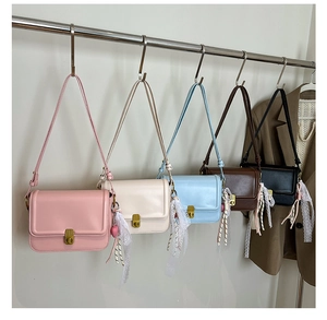 Detail of five colorful leather crossbody bags with gold buckles and lace lace ribbon charms