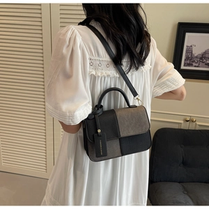 Detail of a two-tone crossbody bag with woven texture, leather strap and fashion tag