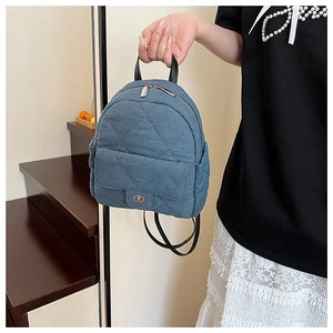 Detail of light blue quilted denim backpack with vintage metal twist lock and leather handle