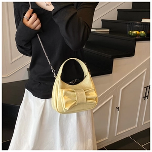 Sac croissant jaune crème avec grand nœud et chaîne argentée porté par un mannequin