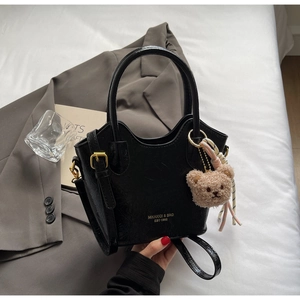 Dettaglio borsa a secchiello nera in finta pelle con orsetto di peluche e foulard di seta