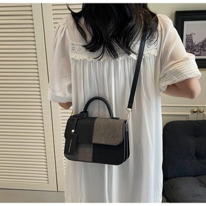 Detail view of the black and grey patchwork handbag from a model's back perspective