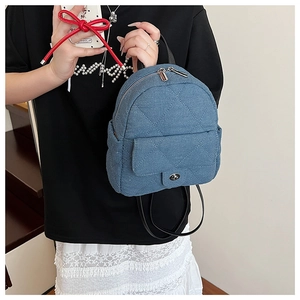Close-up of quilted denim backpack with metallic turn-lock and double zipper detail