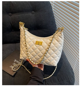 Detailed view of white quilted crossbody bag with gold chain strap and metal turn-lock