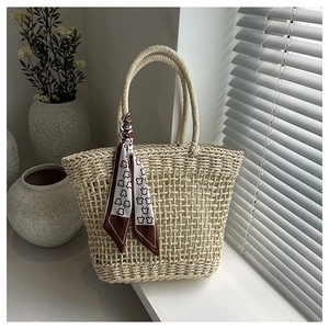 Detail of hollow woven straw tote bag with bear print decorative silk scarf
