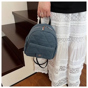 Detail of denim mini backpack featuring diamond quilting and metallic twist lock