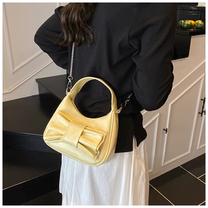 Détail du sac hobo croissant jaune avec grand nœud et bandoulière chaîne argentée sur l'épaule