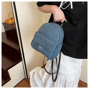 Detail of blue quilted denim mini backpack with silver twist lock and leather handle