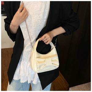 Sac à bandoulière crème avec nœud porté par un mannequin montrant le design chic