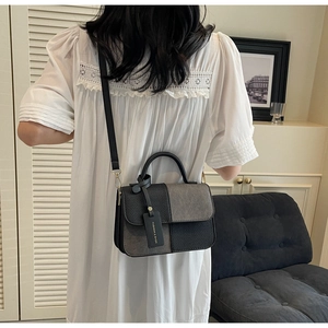 Detail of grey and black patchwork handbag showing woven texture and fashion tag