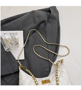 Close-up of white quilted leather chain bag with a metal twist lock on a grey blazer