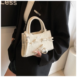 Détail du sac à main blanc crème plissé avec nœuds 3D et perles porté par un mannequin