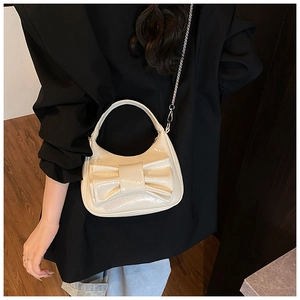 Détail du sac croissant en cuir verni crème avec grand nœud et bandoulière en chaîne