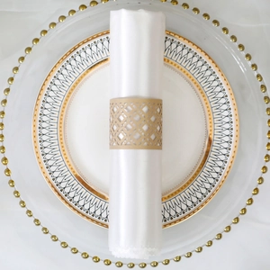 Detail of laser-cut geometric gold napkin ring on a white silk napkin and elegant plate
