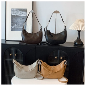 Detail of four crescent shoulder bags in brown, black, cream, and tan textured leather