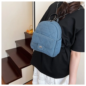 Detail of blue denim backpack featuring diamond stitching and silver chain strap