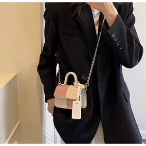 Mini corduroy patchwork bag in pink and beige with gold chain strap worn on black suit
