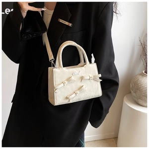 Détail d'un sac bandoulière blanc crème chic avec nœuds 3D élégants et perles