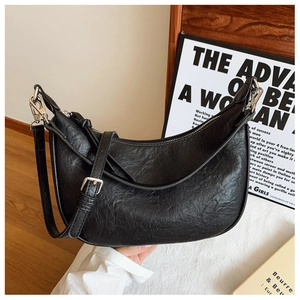 Detail of black pleated faux leather half-moon bag with silver hardware and knot detail