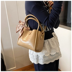 Détail d'un sac seau kaki avec motif crocodile et foulard décoratif élégant