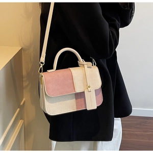 Fashionable patchwork crossbody bag with pastel colors worn by a model in a black suit