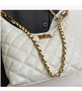 Detail of white quilted crossbody bag with gold chain strap and glossy leather finish