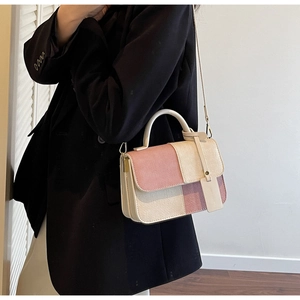 Detail of a textured patchwork handbag in pastel pink and beige with a leather tag