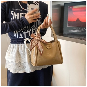 Détail d'un sac à main marron clair à motif crocodile avec foulard en soie décoratif