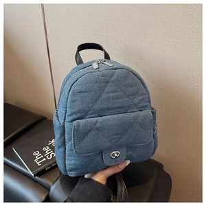 Detailed macro of denim blue mini backpack with silver metal zipper and diamond quilting