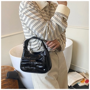 Détail du sac croissant en cuir verni noir avec grand nœud et fine bandoulière chaîne