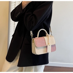 Detail of color-block patchwork handbag with straw texture and gold metal buckle