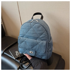 Detail of blue denim mini backpack featuring quilted pattern and silver metal clasp