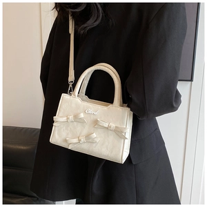 Gros plan du sac plissé blanc crème orné de nœuds délicats et de détails en perles