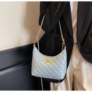 Detail of light blue quilted patent leather bag with gold buckle and chain strap