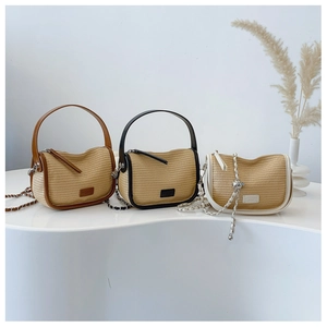 Three straw woven shoulder bags in brown, black and white trim on minimalist display