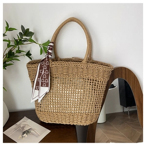 Macro detail of hand-woven hollow mesh tote bag with a decorative silk scarf handle