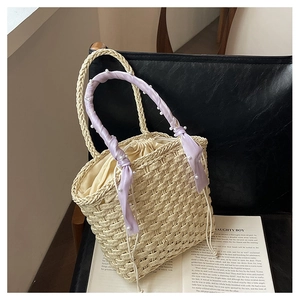 Detail of beige woven bucket bag with pearl accents and lavender silk ribbon on a chair