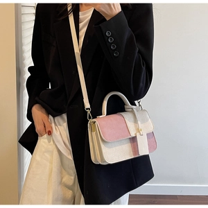 Detail of pink and beige patchwork crossbody bag with textured woven surface on a model
