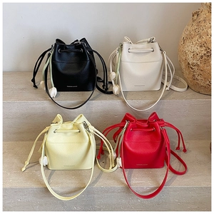 Close-up of four colored leather bucket bags with tulip charm and litchi grain texture