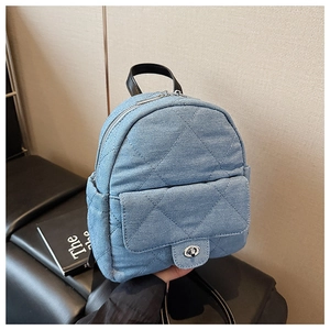 Close-up of light blue quilted denim backpack with silver twist lock and dual-way zipper