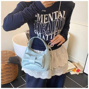 Détail d'un sac croissant bleu clair orné d'un grand nœud et d'une bandoulière chaîne