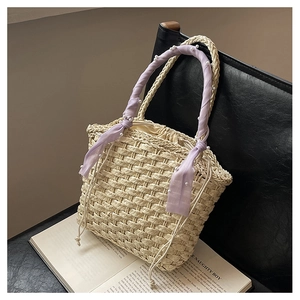 Detail of straw bucket bag featuring purple scarf handle and pearl accents on chair