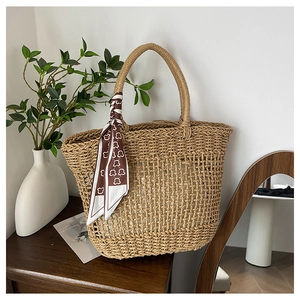 Detailed close-up of handmade woven straw tote bag with decorative bear print scarf handle