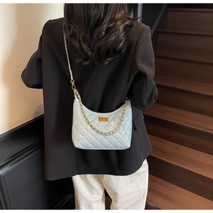 Detail view of light blue quilted chain shoulder bag with gold turn-lock and patent finish